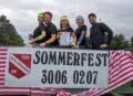 Fünf Personen posieren über dem Sommerfest-Banner
